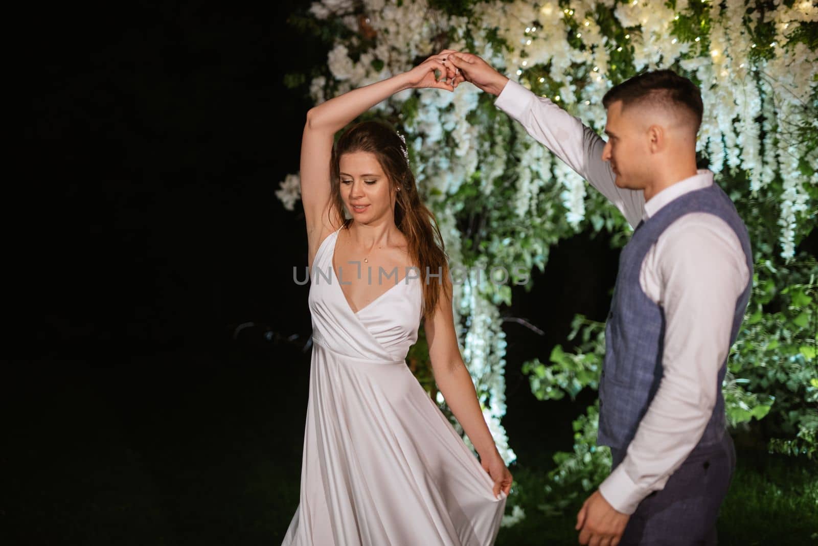 young couple of newlyweds on the evening illuminated arch