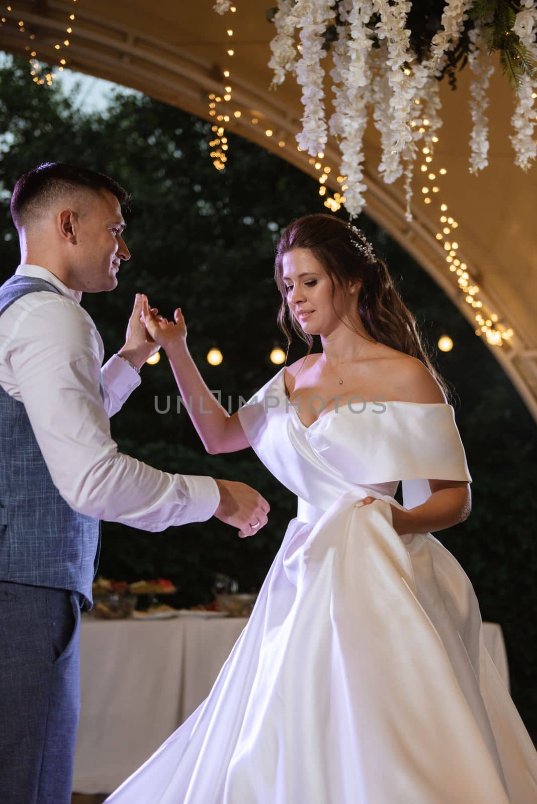 the first wedding dance of the bride and groom inside the restaurant hall in sunset light