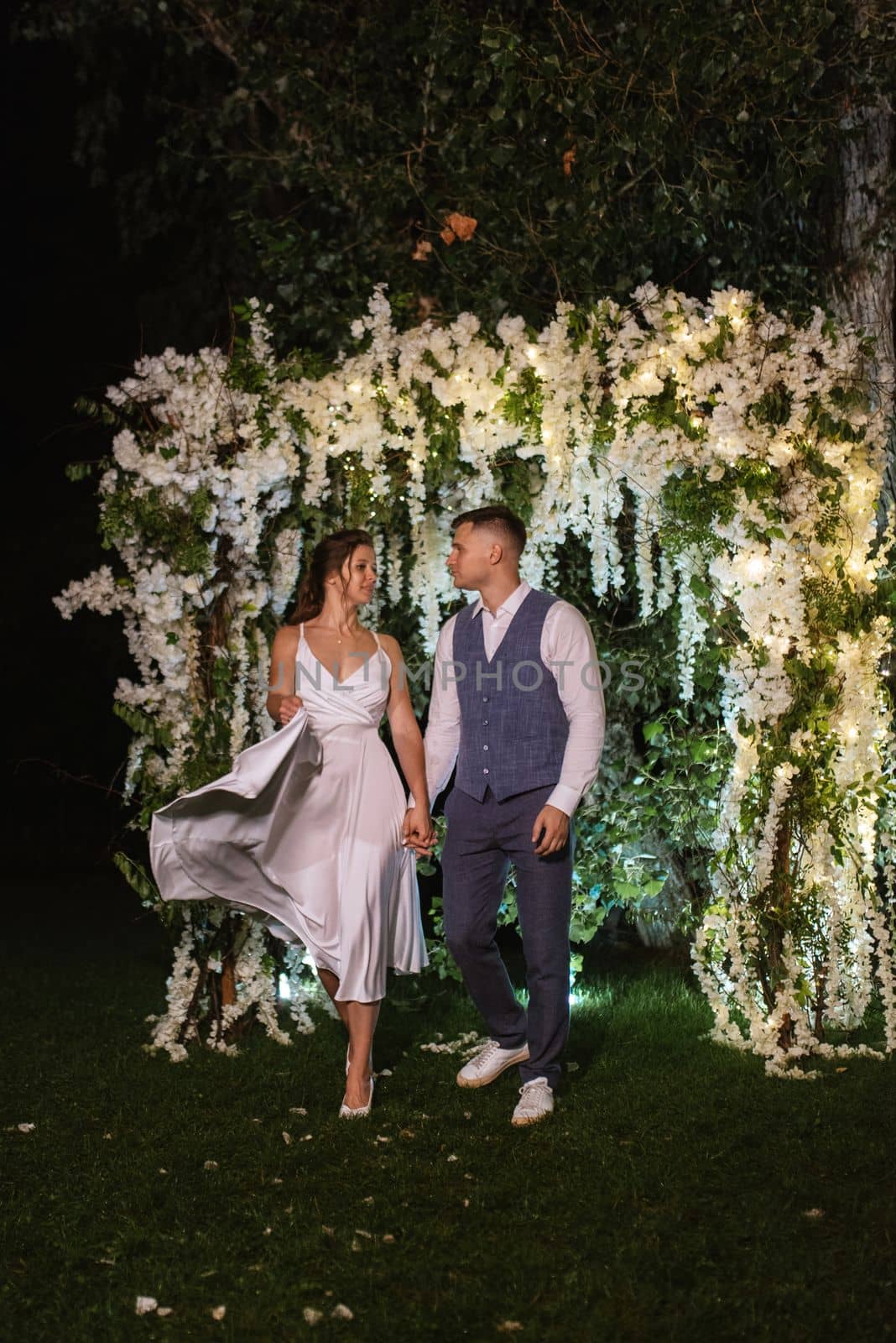 young couple of newlyweds on the evening illuminated arch