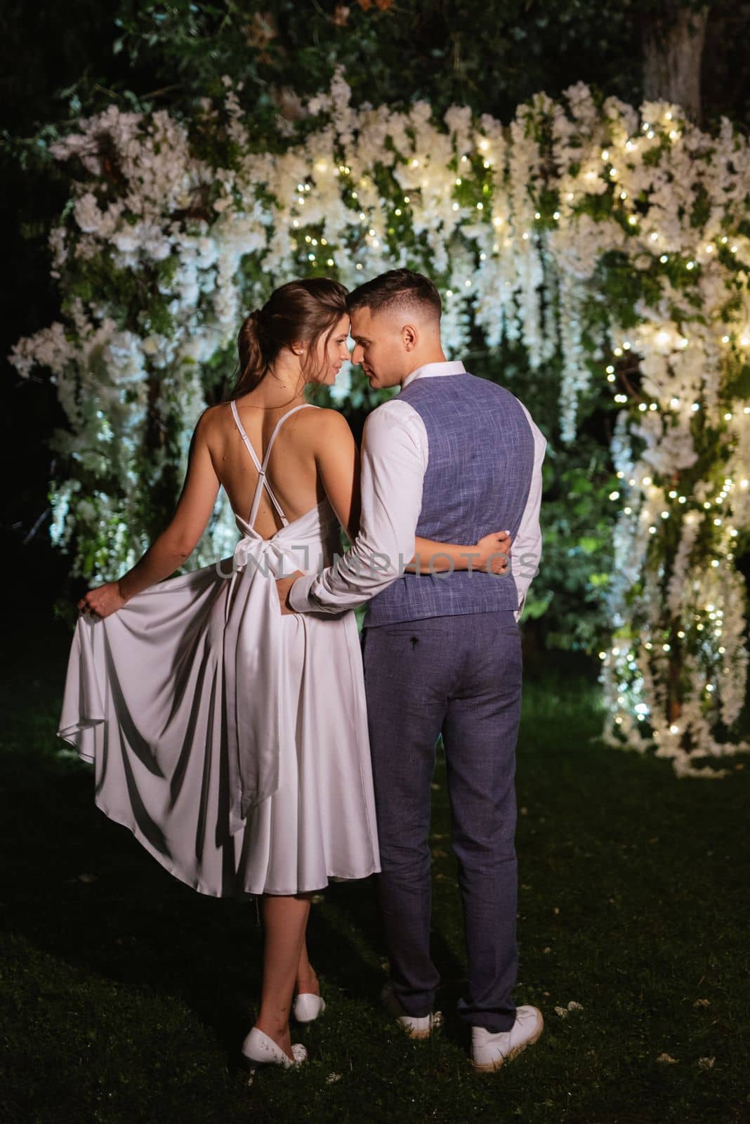 young couple of newlyweds on the evening illuminated arch