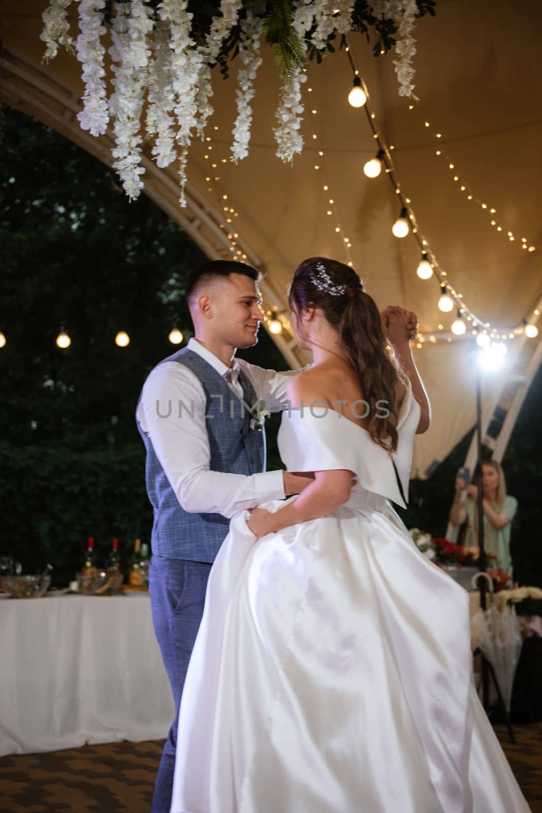 the first wedding dance of the bride and groom inside the restaurant hall in sunset light