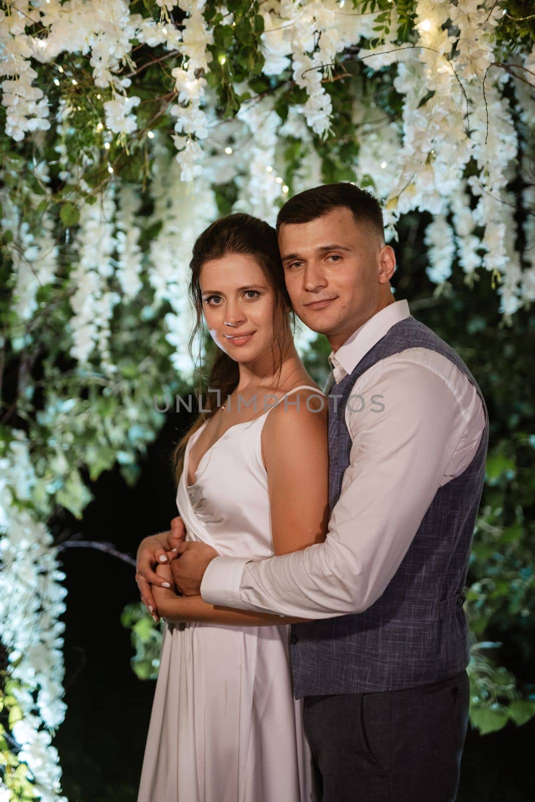 young couple of newlyweds on the evening illuminated arch