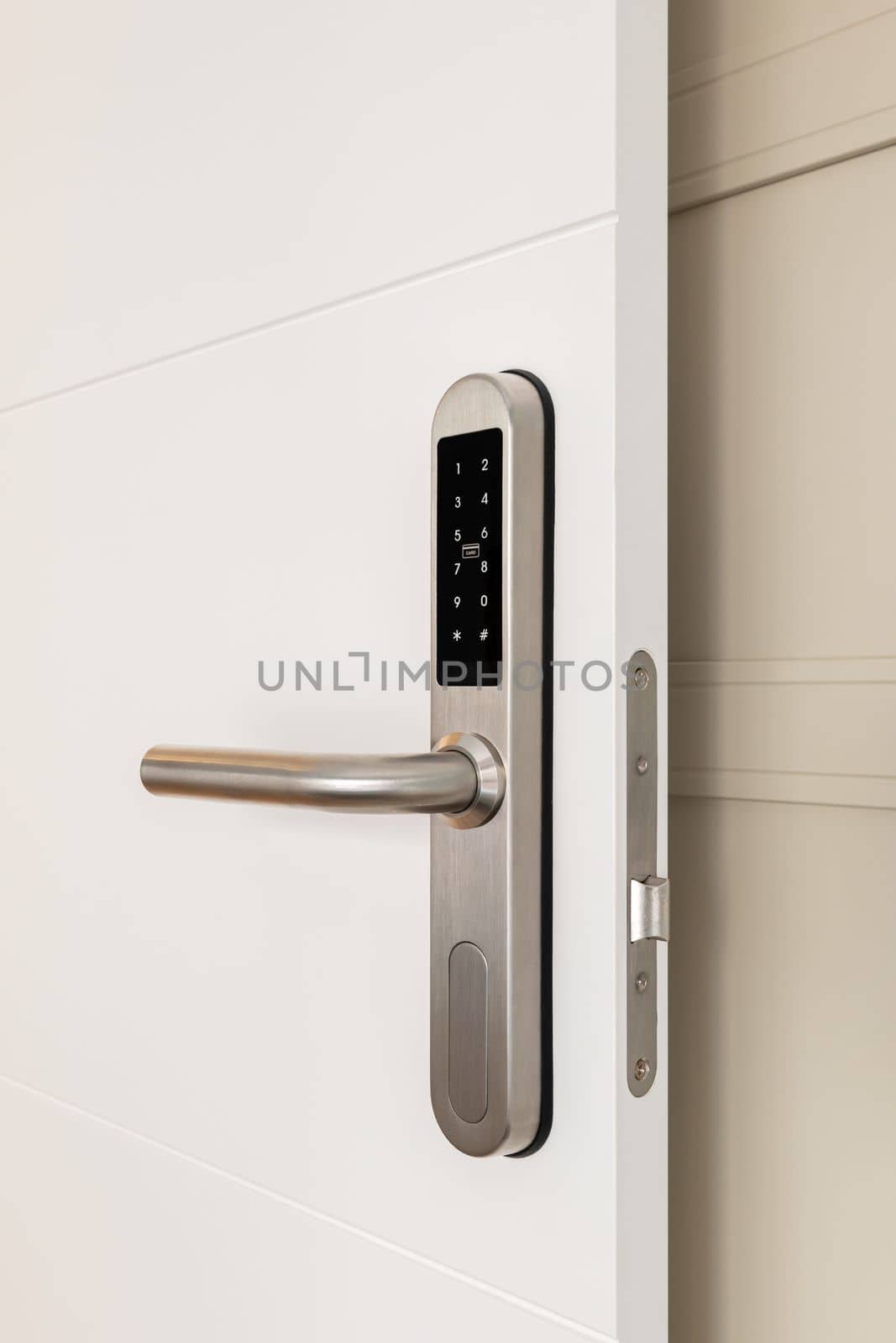 Entrance white wooden door with an electronic lock for the security of the apartment. On the lock there are buttons with numbers for entering the code. Chrome metal lock