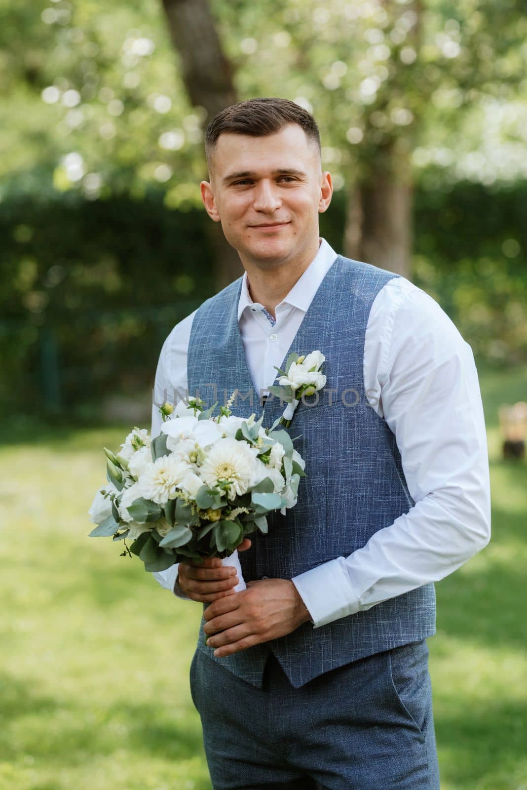 portrait of the groom in a light gray suit outdoors