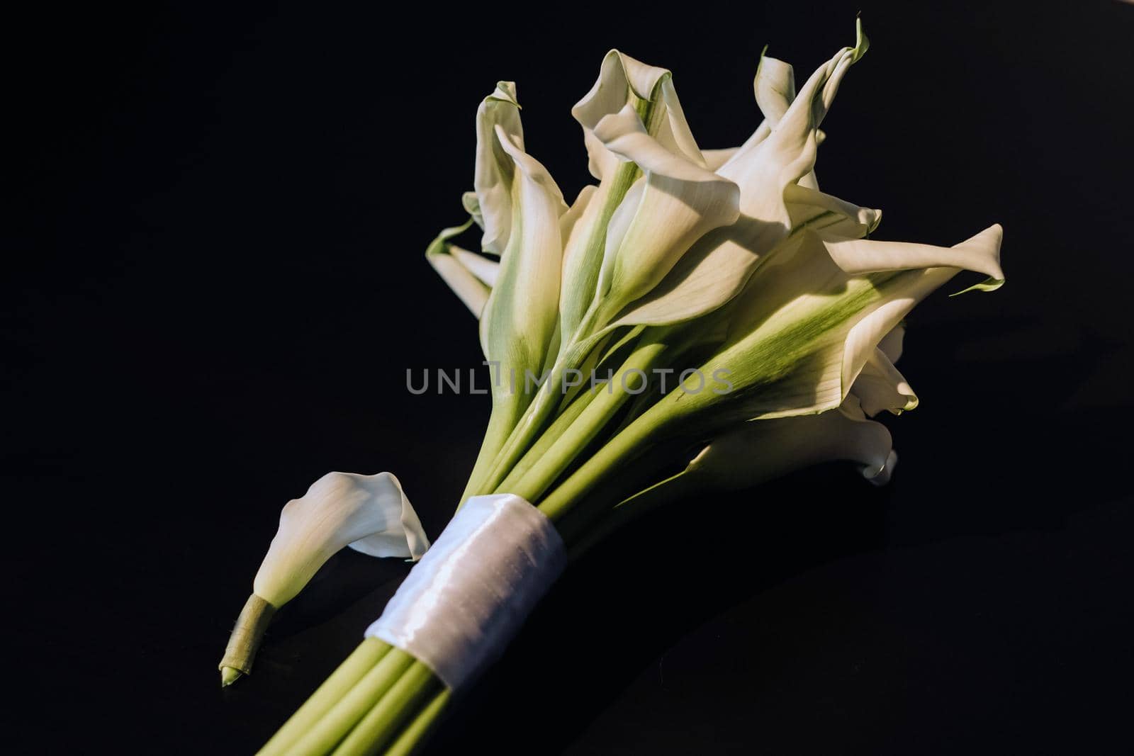 Wedding bouquet of white Calla lilies on a black background.