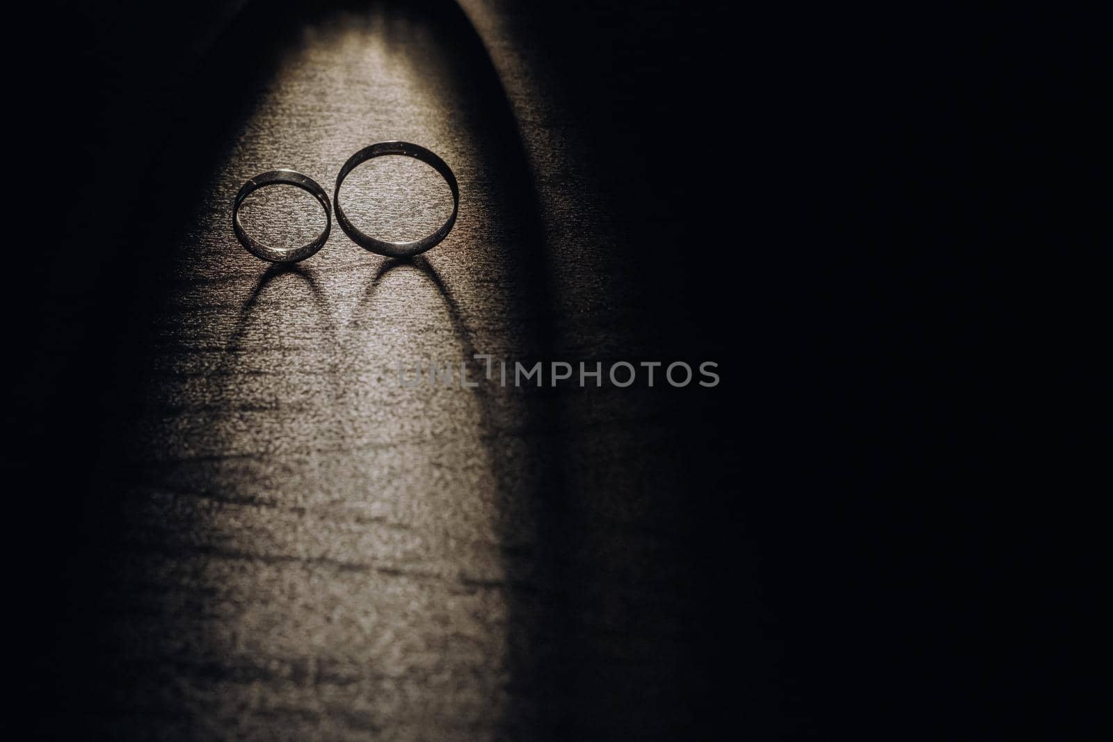 Close-up of two gold wedding rings on a black background by Lobachad