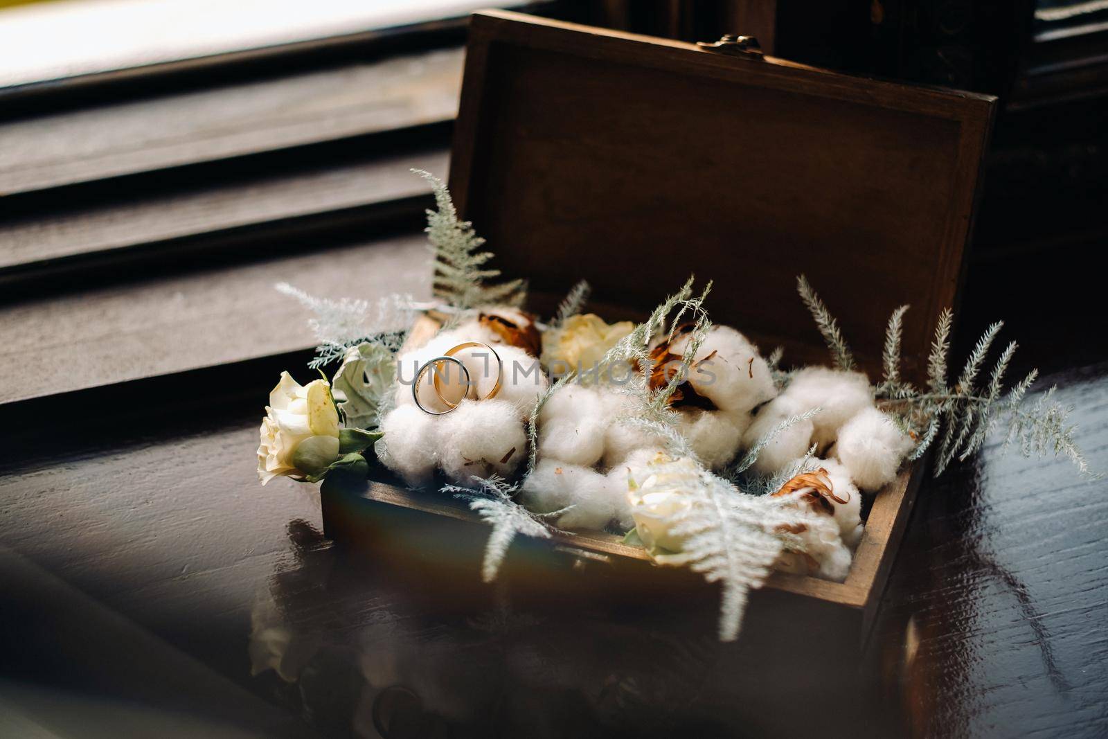 Close-up of two gold wedding rings for a wedding in a decorative box with flowers.