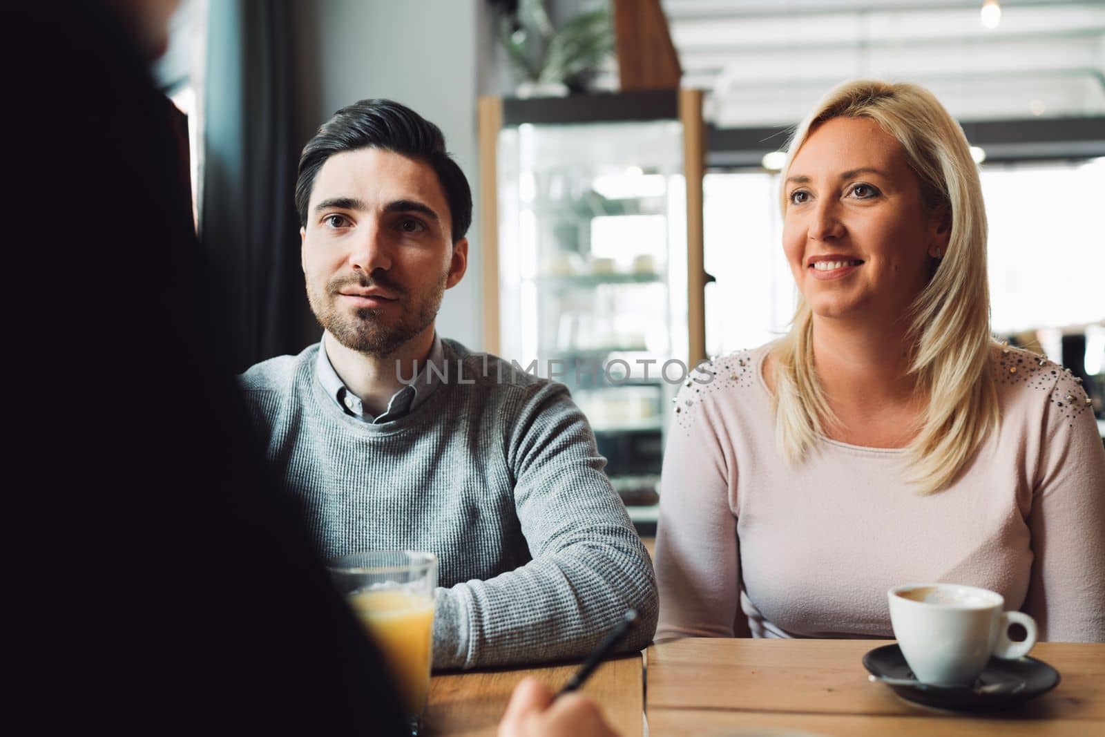 Smiling caucasian couple sitting at the desk across from their financial advisor, carefully listening to what he is saying by VisualProductions