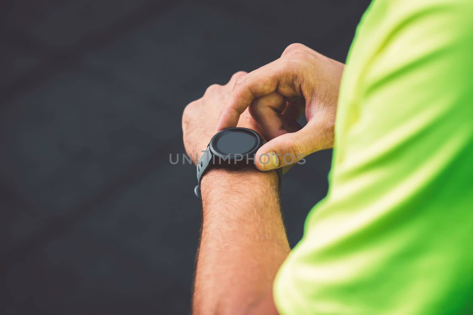 Close up man in green shirt setting his sports watch activity by VisualProductions