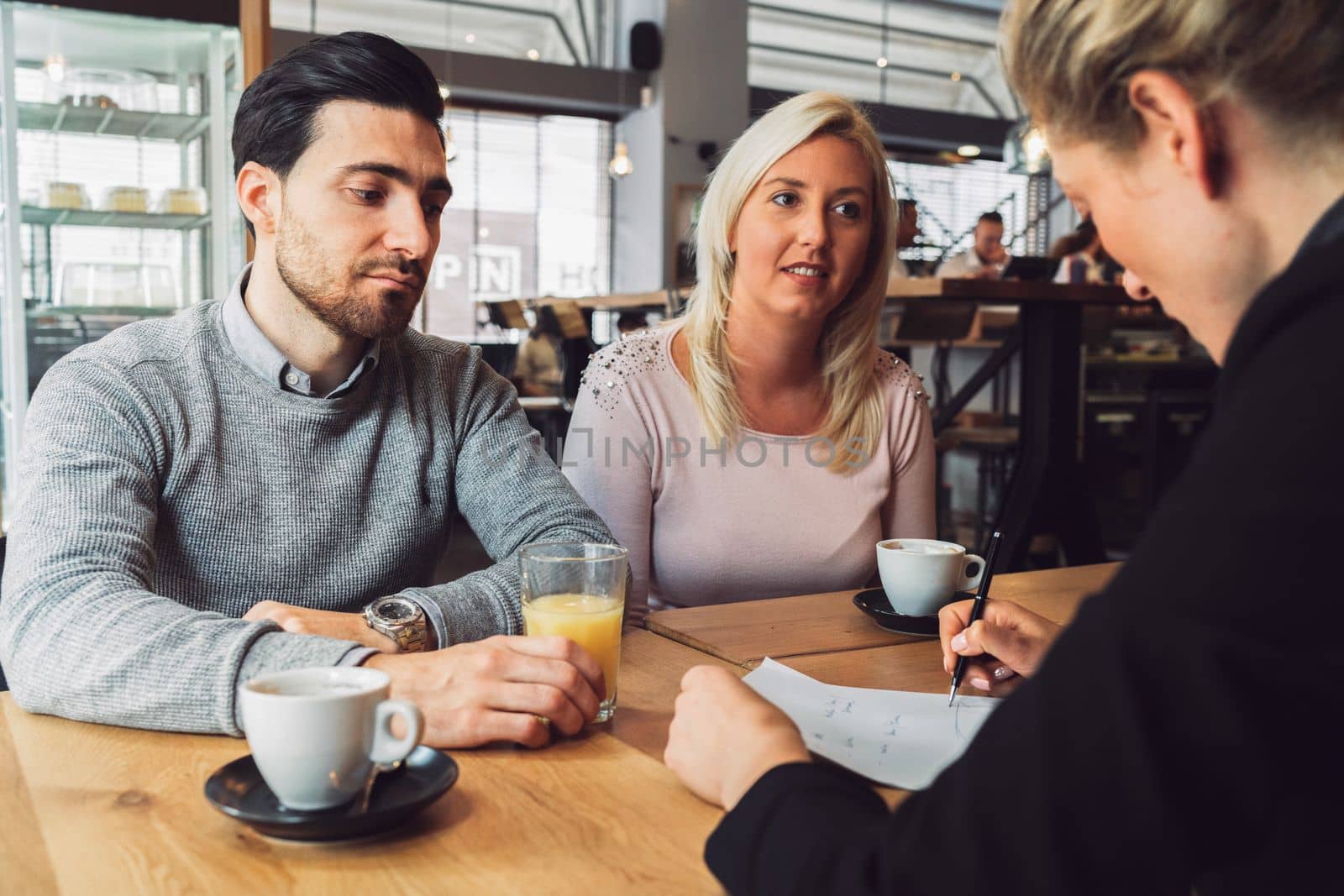 Meeting with clients. Caucasian woman, designer, meeting with her clients, sitting by the desk, consulting on a project. Business meeting. Caucasian people having a meeting in an office.