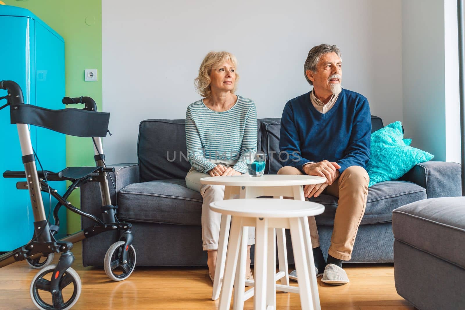 Senior couple sitting on the couch at the nursing home looking out the window.