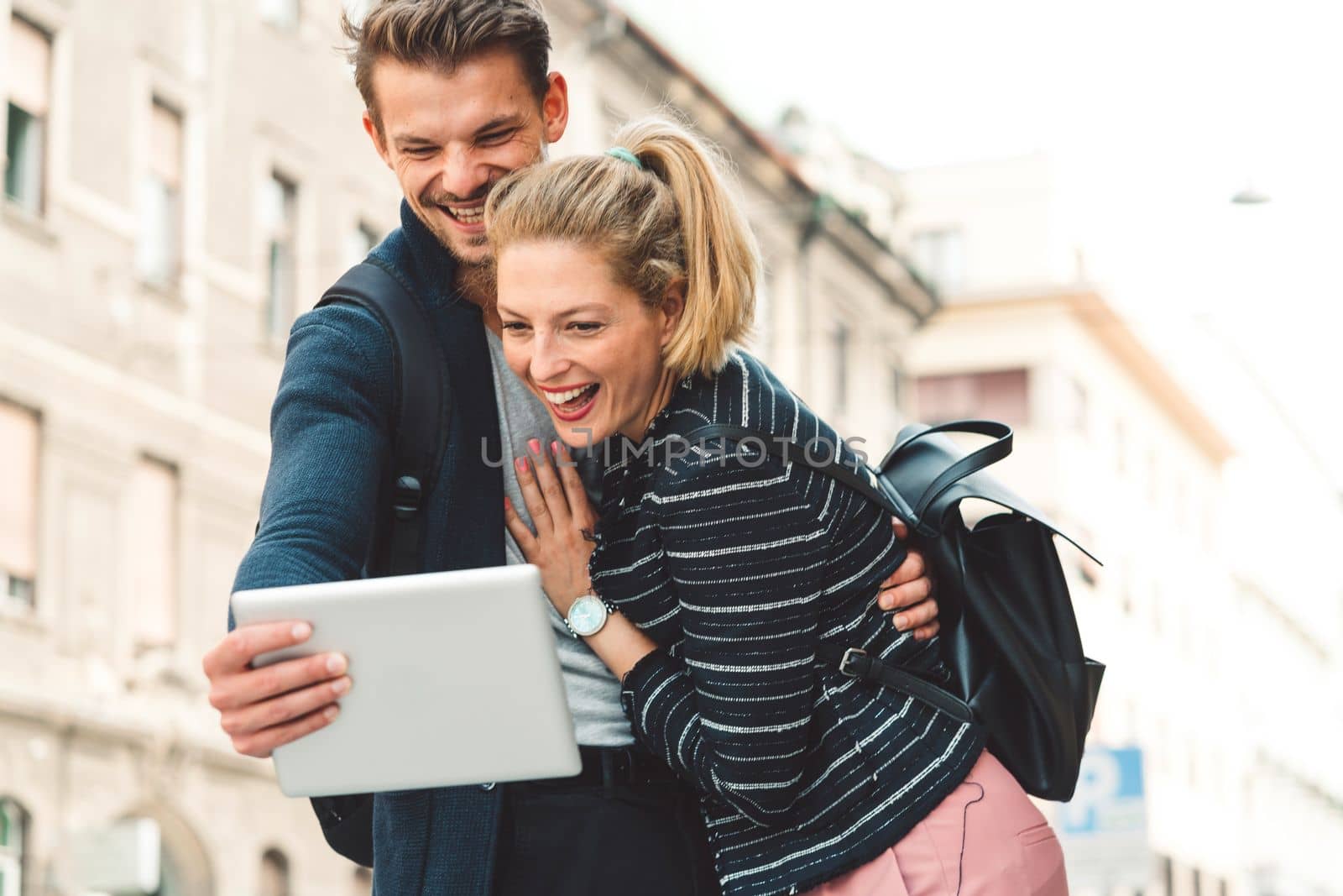 Young millennial couple living in the city, taking a selfie with a smart phone.