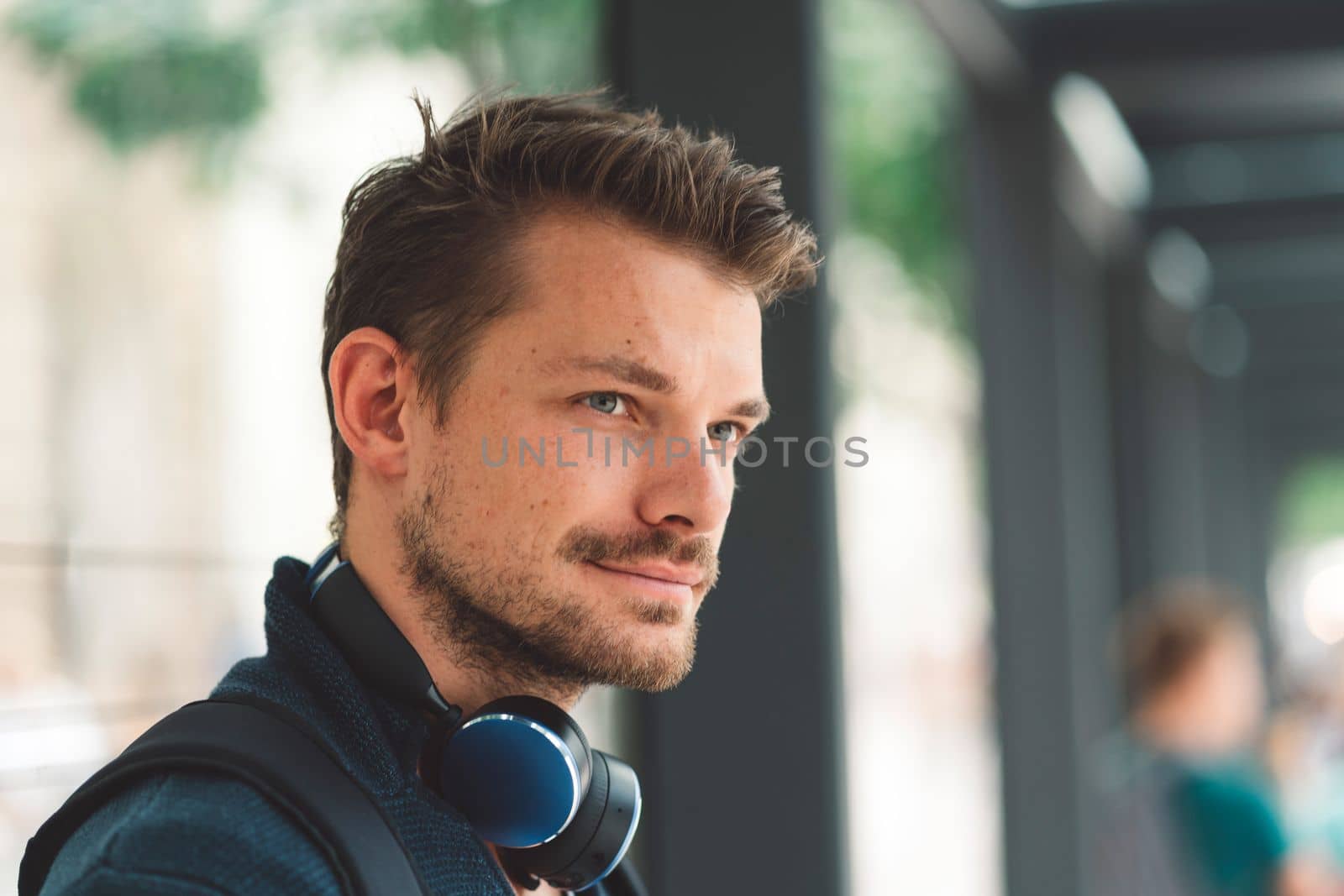 Beautiful caucasian man living in the city. Man spending his day in the city, sun is shining, weather is nice. Young millennial person living in the city, doing his daily errands always using his digital devices, tablet or phone.