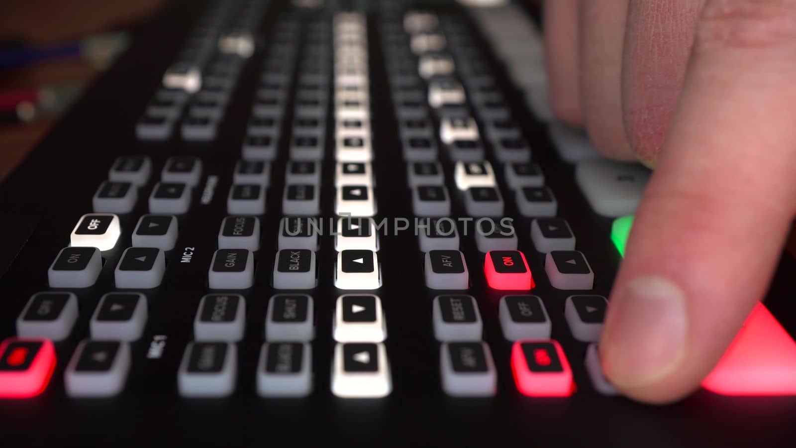 An engineer operates a digital video mixer. A man switches buttons on the camera control panel. Hand close up. 4k