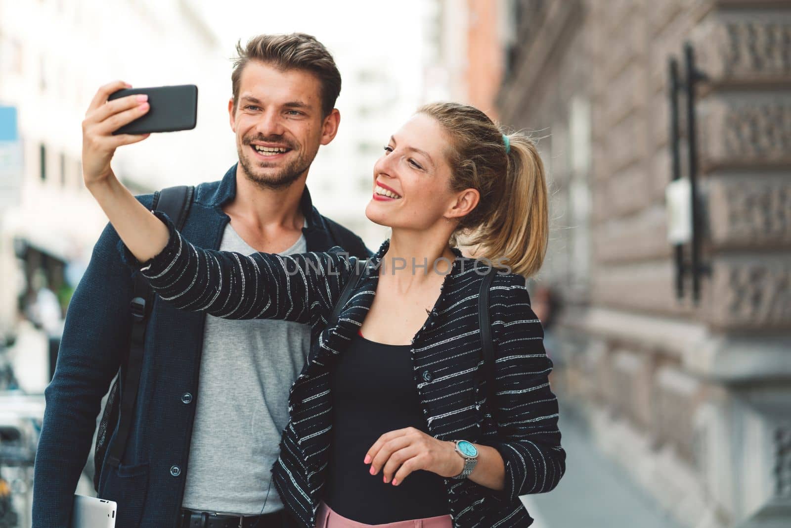 Young millennial couple living in the city, taking a selfie with a smart phone.