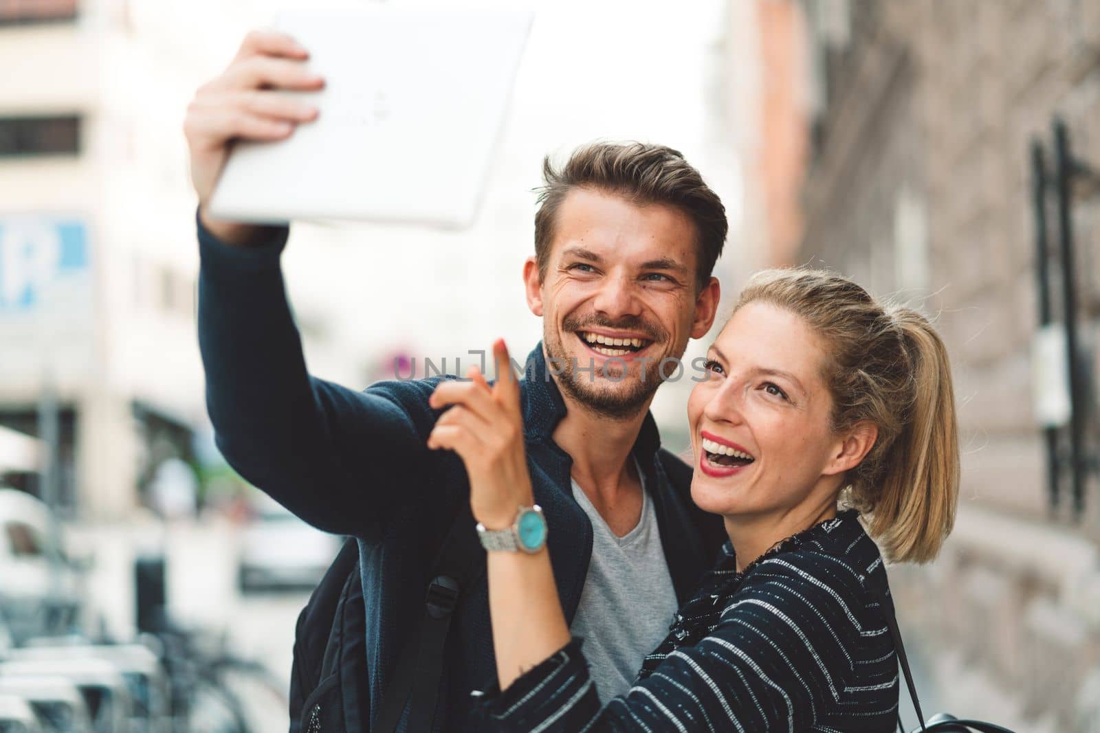 Happy caucasian couple taking selfies in the city on a sunny day by VisualProductions