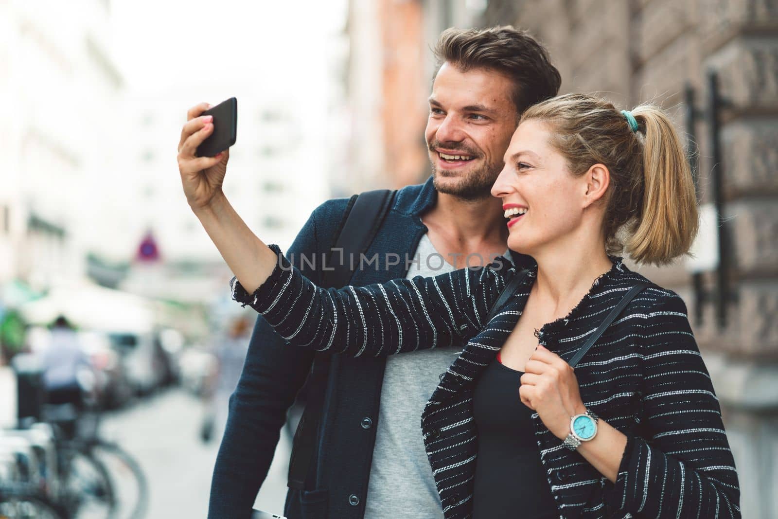 Young millennial couple living in the city, taking a selfie with a smart phone.