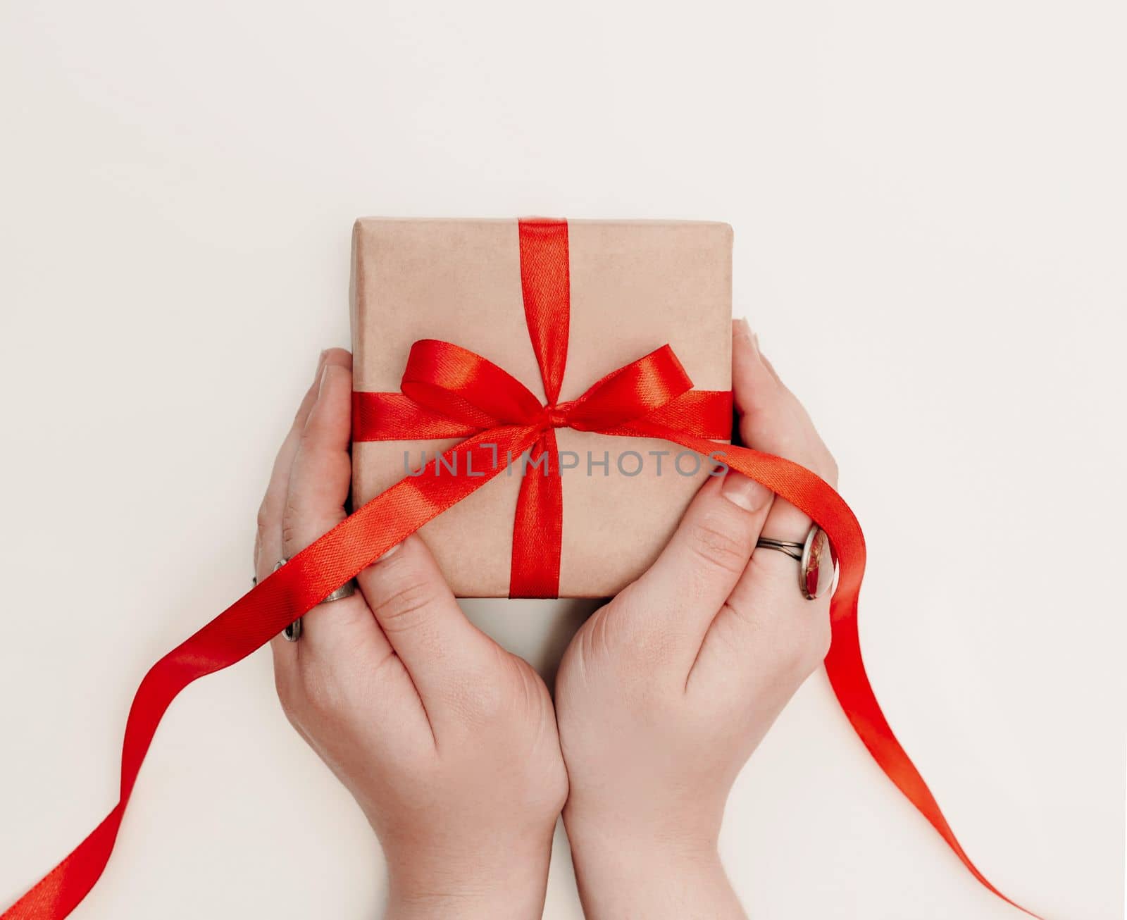 Hand red gift. Women's hands hold a present for christmas or valentine's day. Isolated on white background. View from above.