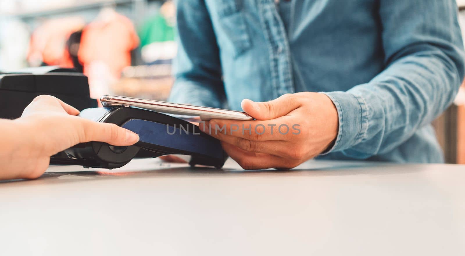 Young caucasian person using a wireless payment method. Young person holding her credit card next to a card reader, paying for her coffee.