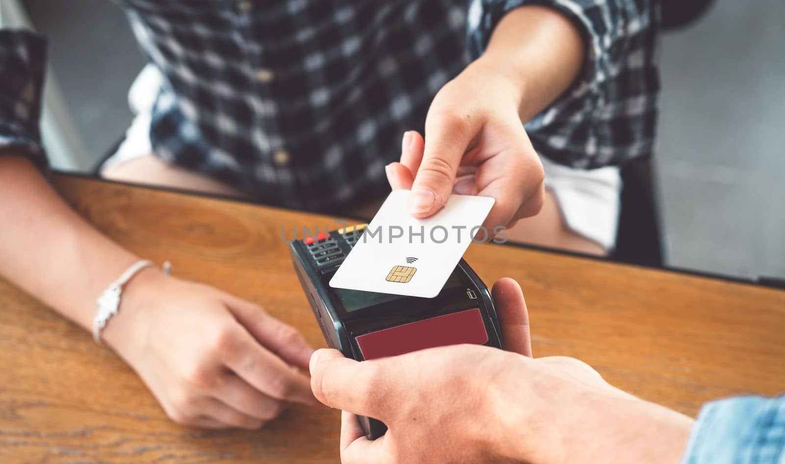 Person hand holding a credit card next to the card reader paying for his shopping by VisualProductions