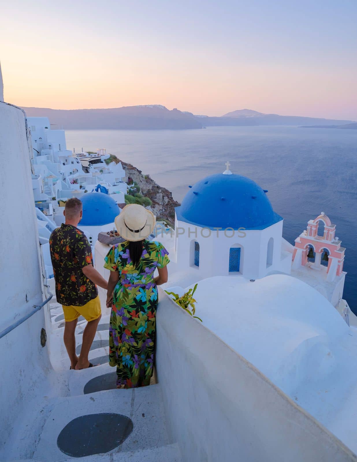 A couple walking at the village of Oia Santorini Greece, men and women visit the whitewashed Greek village of Oia during summer vacation