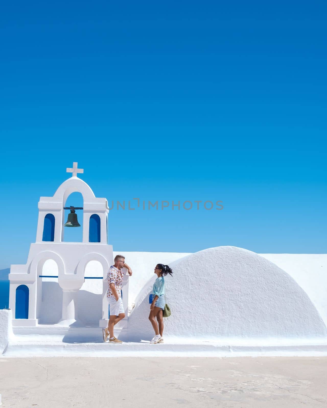 Couple on vacation in Santorini Greece, and men and women at the Greek village of Oia with a view over the ocean during summer vacation