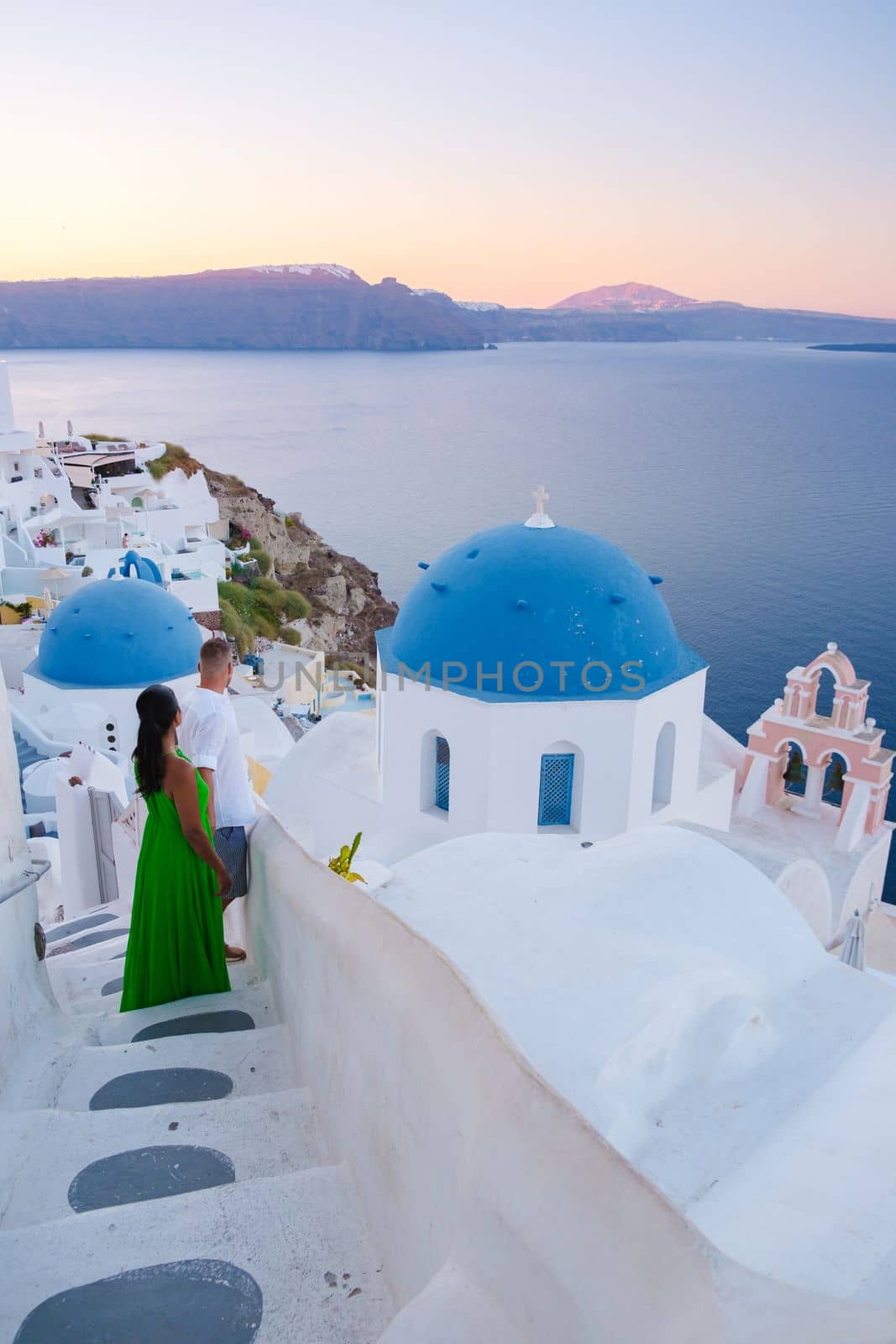Couple on vacation in Santorini Greece, and men and women at the Greek village of Oia with a view over the ocean during summer vacation