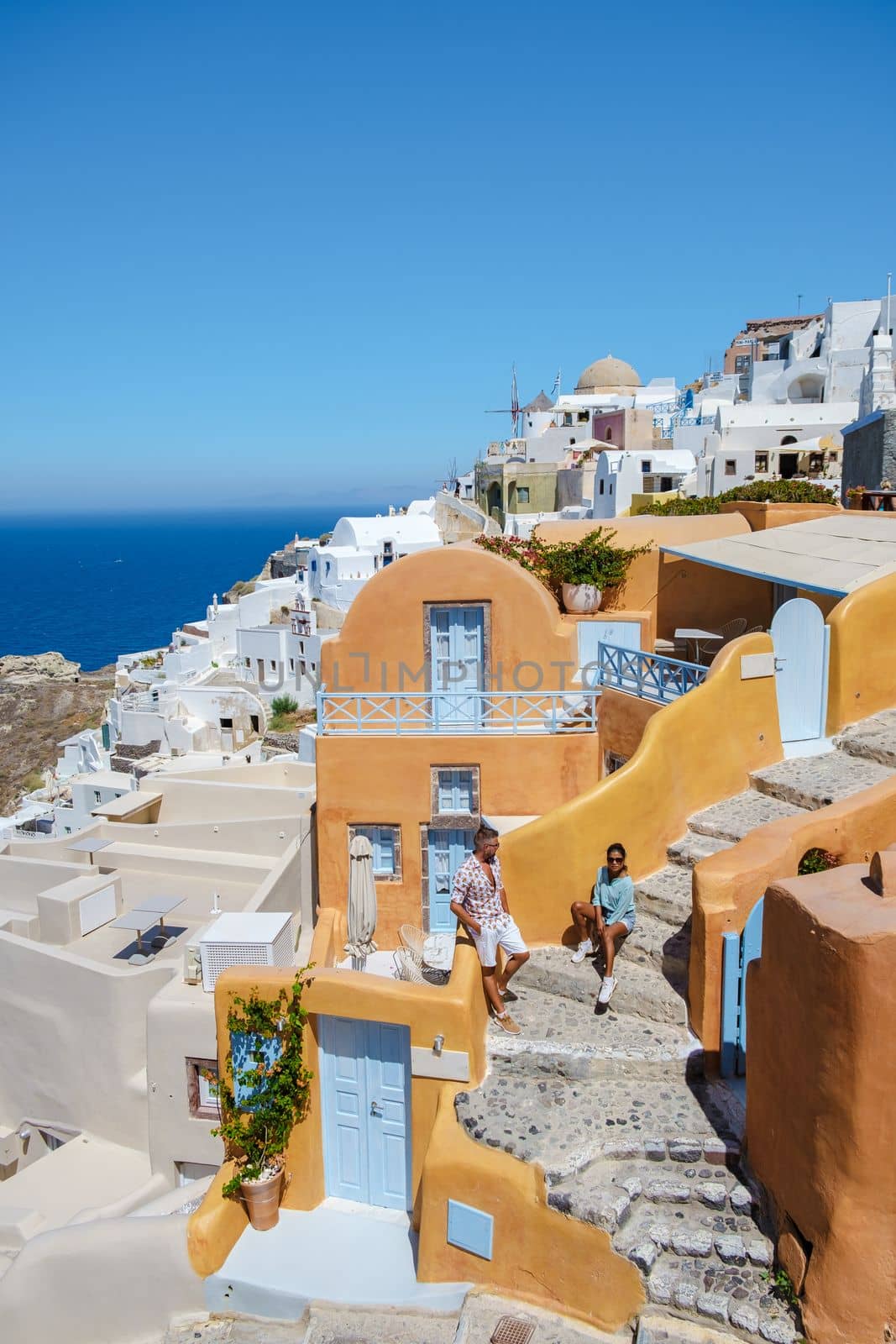 Couple on vacation in Santorini Greece, and men and women at the Greek village of Oia with a view over the ocean during summer vacation