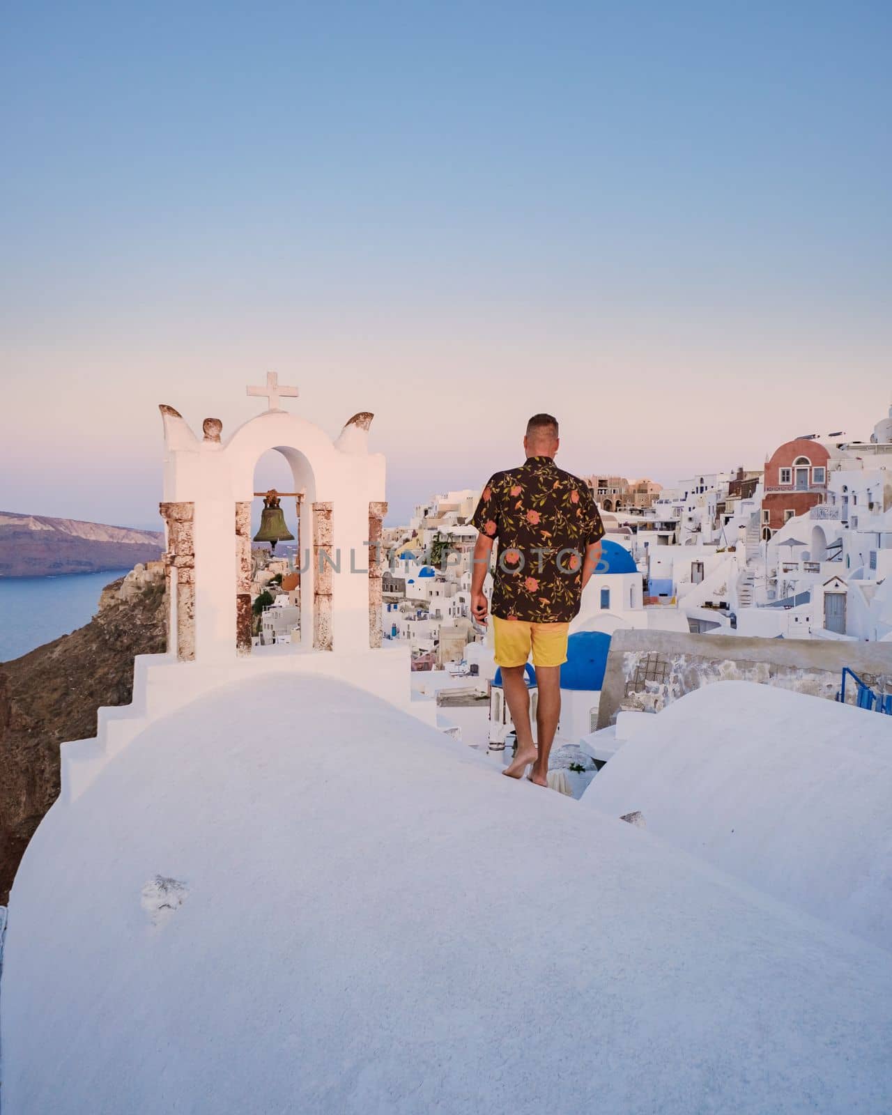 Young men watching sunrise in Santorini Greece, man on vacation at the Greek village Oia by fokkebok