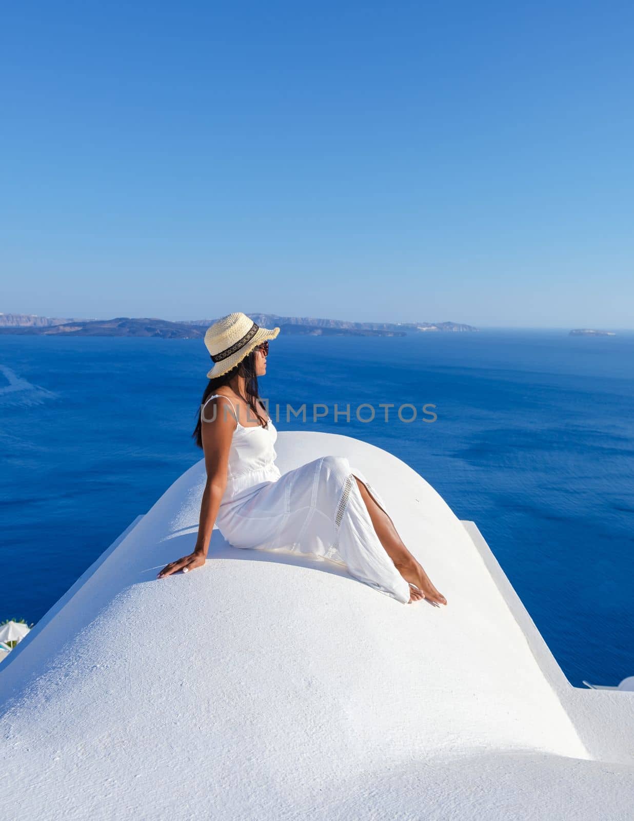 Young Asian women on vacation in Santorini Greece, a girl with hat at the Greek village in Santorini.