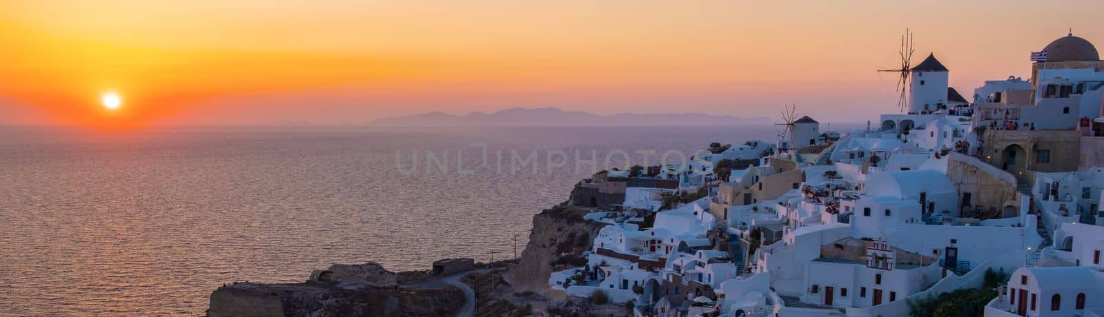 sunset with white churches an blue domes by the ocean of Oia Santorini Greece, a traditional Greek village in Santorini.