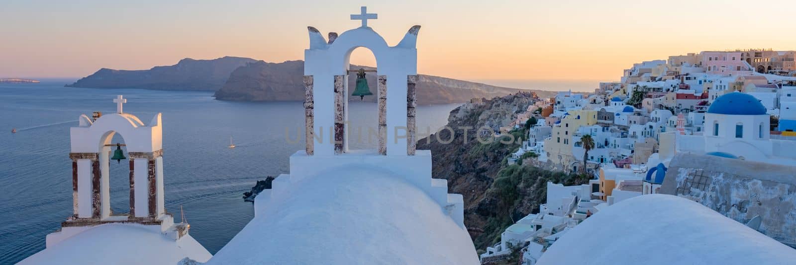 White churches an blue domes by the ocean of Oia Santorini Greece, a traditional Greek village in Santorini during summer