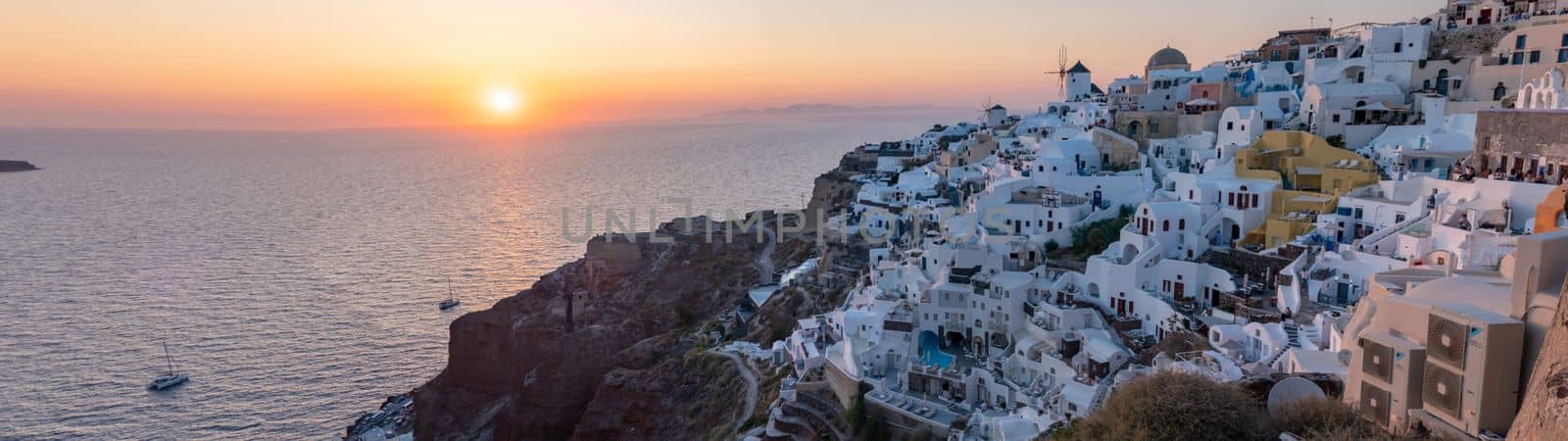 Sunset with white churches an blue domes by the ocean of Oia Santorini Greece by fokkebok