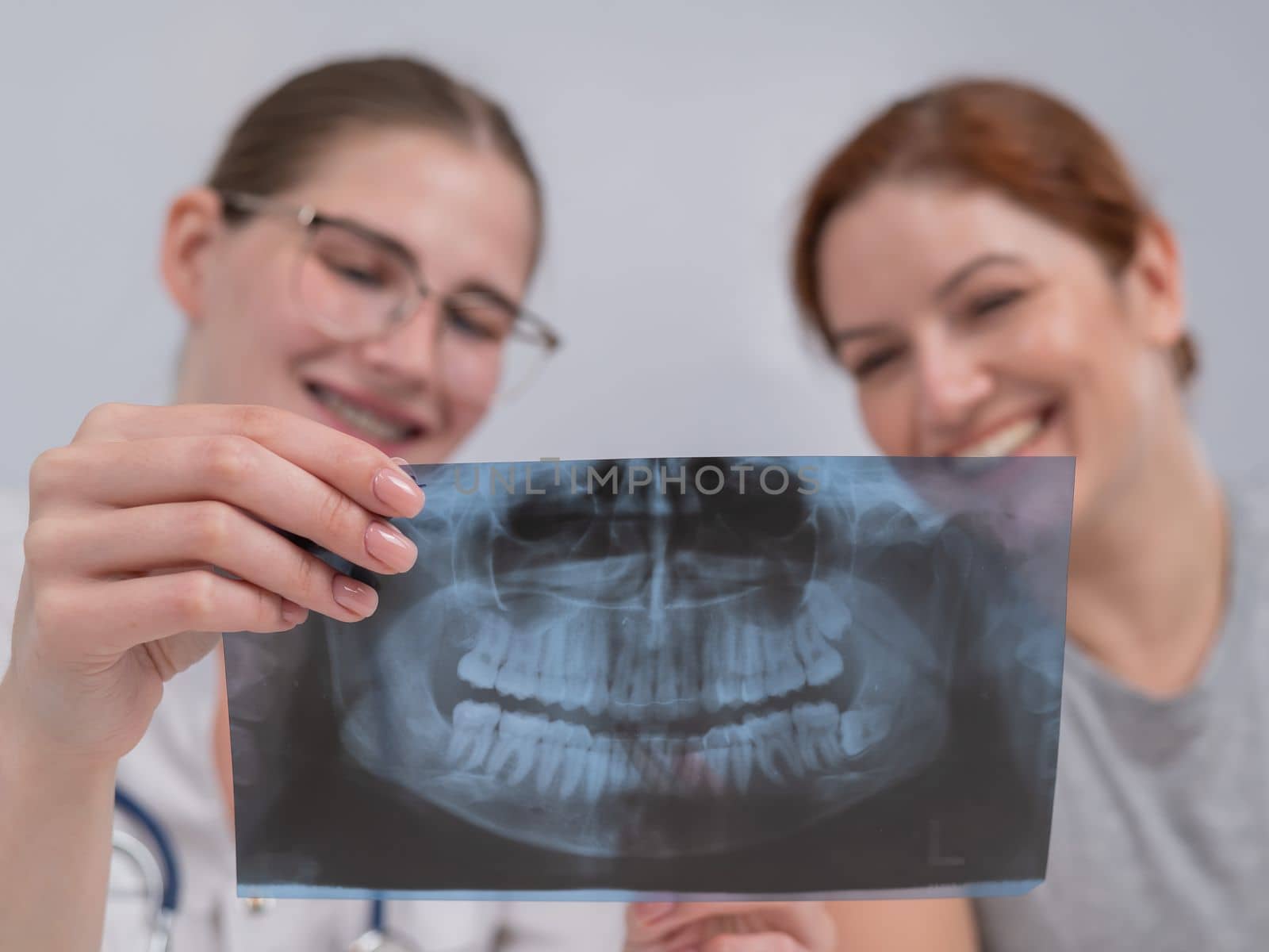 A woman doctor and a patient at the reception are discussing an x-ray of the jaw. by mrwed54