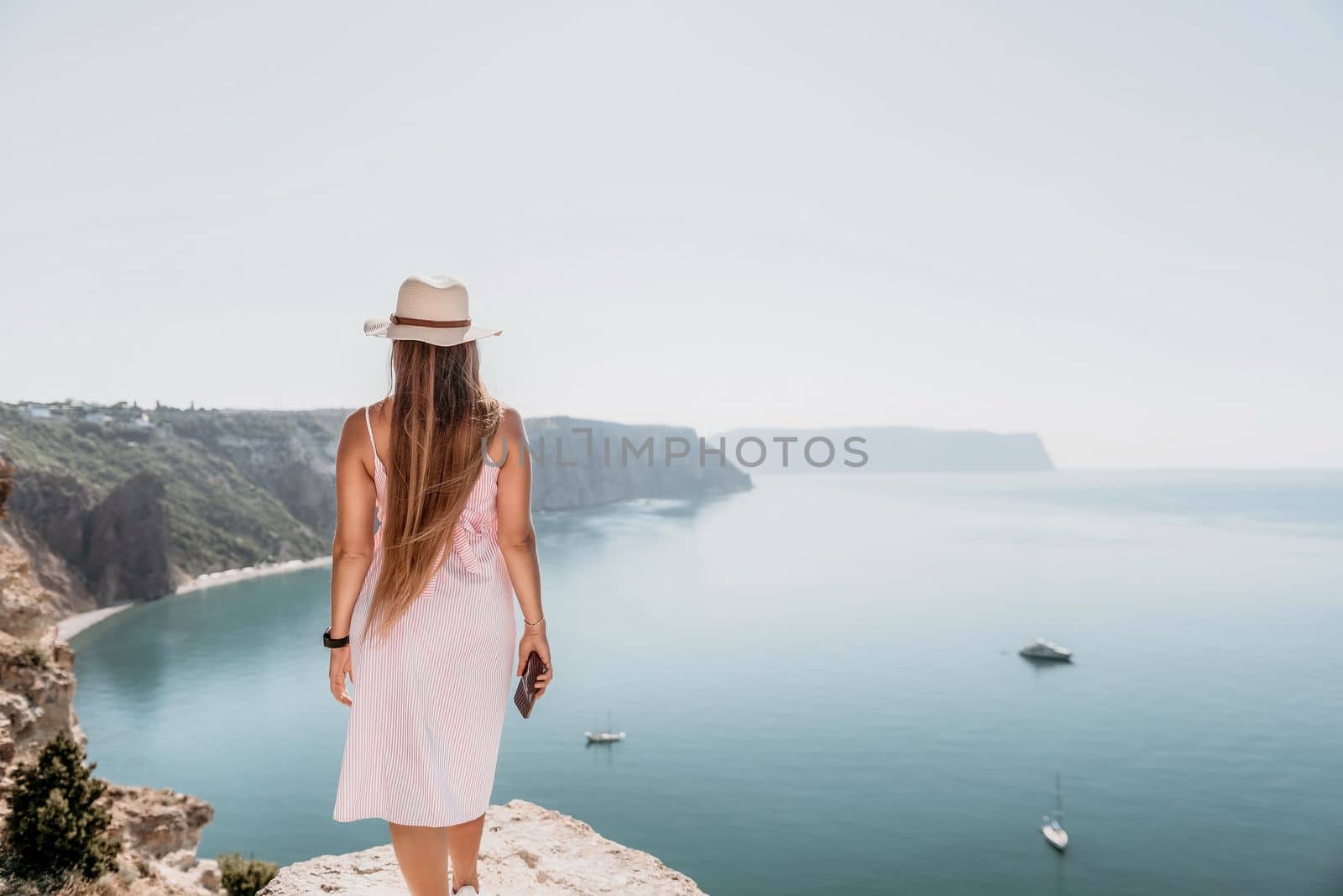 Woman sea laptop. Business woman in yellow hat freelancer with laptop working over blue sea beach. Girl relieves stress from work. Freelance, digital nomad, travel and holidays concept by panophotograph