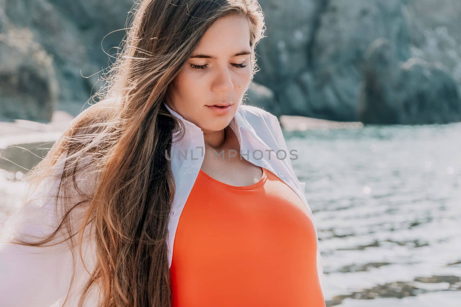 Young woman in red bikini on Beach. Girl lying on pebble beach and enjoying sun. Happy lady with long hair in bathing suit chilling and sunbathing by turquoise sea ocean on hot summer day. Close up by panophotograph