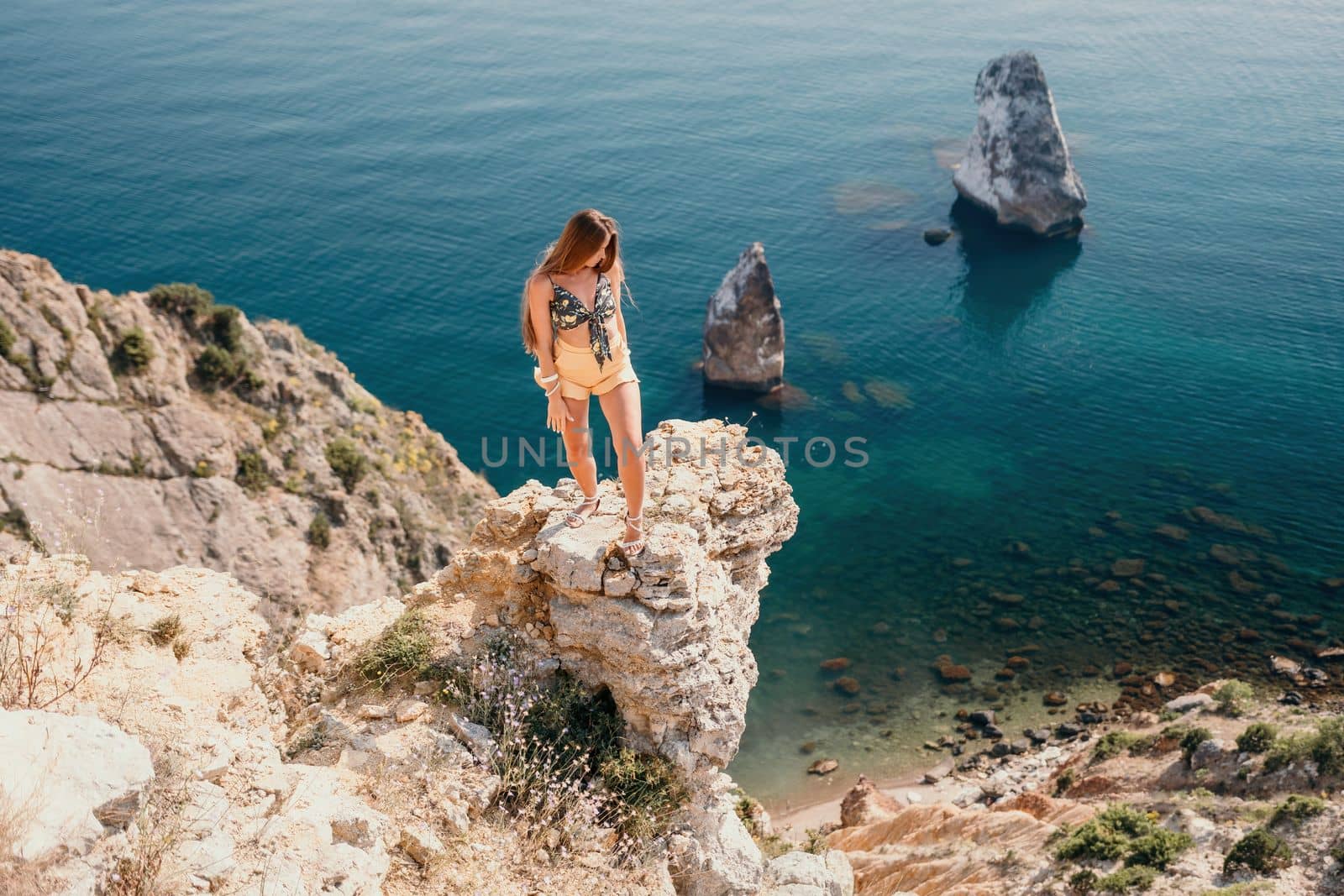 Woman travel sea. Happy tourist enjoy taking picture outdoors for memories. Woman traveler looks at the edge of the cliff on the sea bay of mountains, sharing travel adventure journey by panophotograph