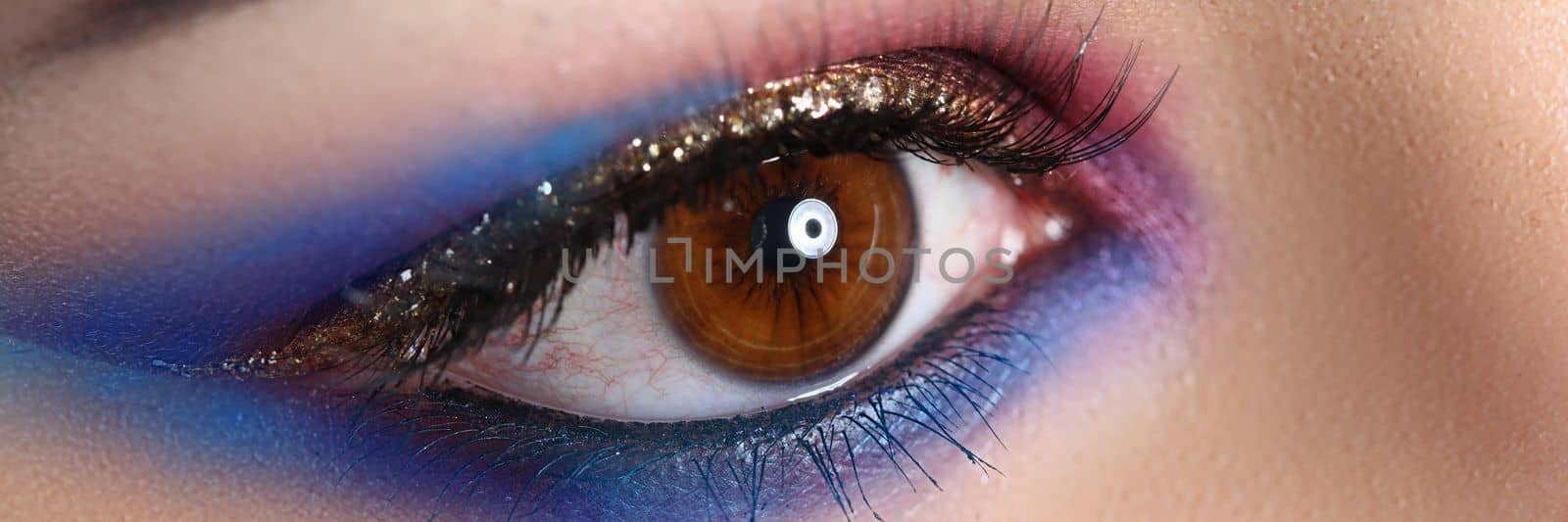 Closeup of brown female eye with beautiful brown red and orange tints smoky eye makeup. Bright evening makeup