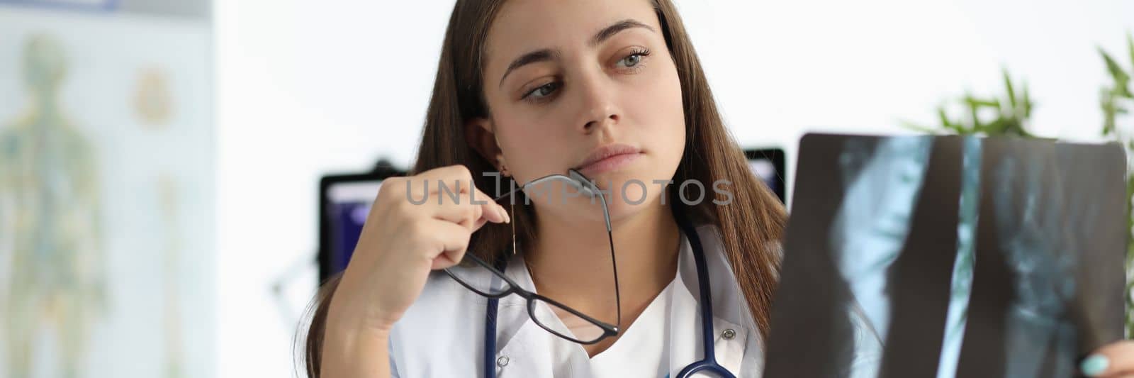 Worried female doctor examining an x-ray of patient by kuprevich