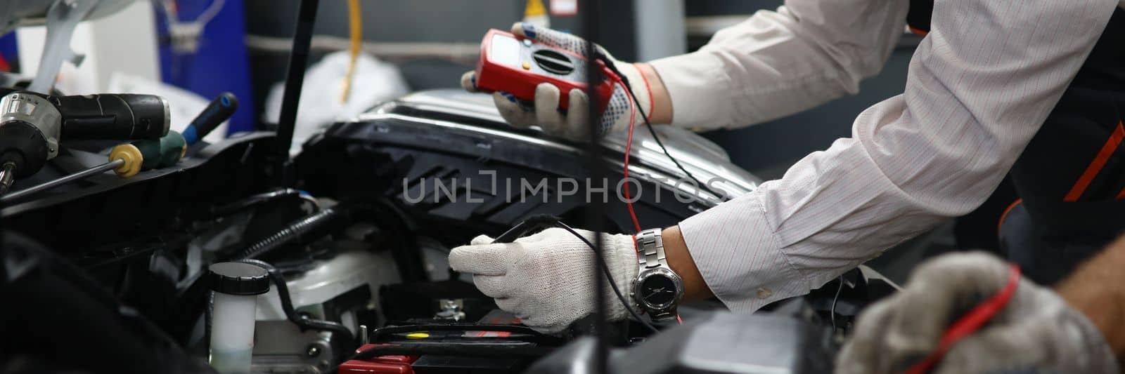 Car repair technicians use voltage multimeter to work in auto repair shops by kuprevich