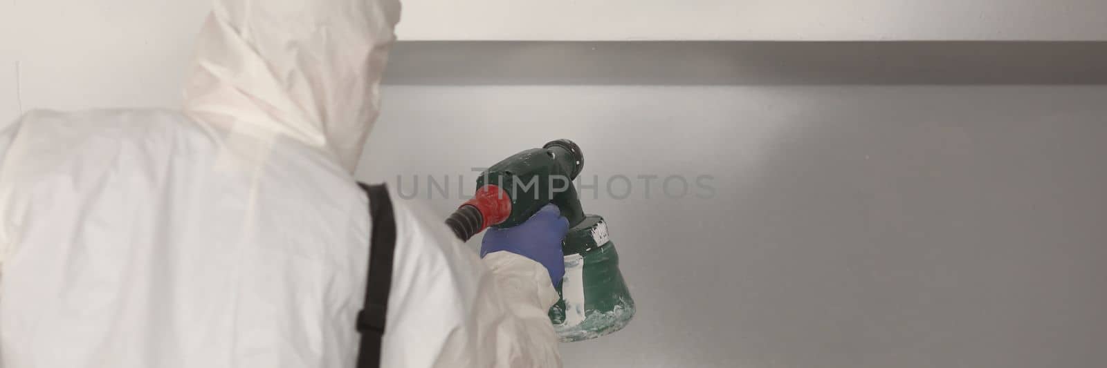 Worker paints wall white with spray gun by kuprevich