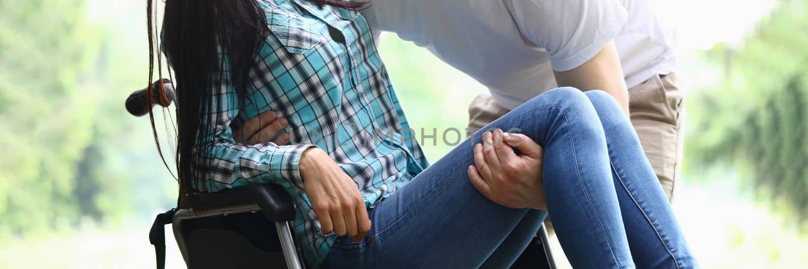 Man helps disabled woman into wheelchair closeup by kuprevich