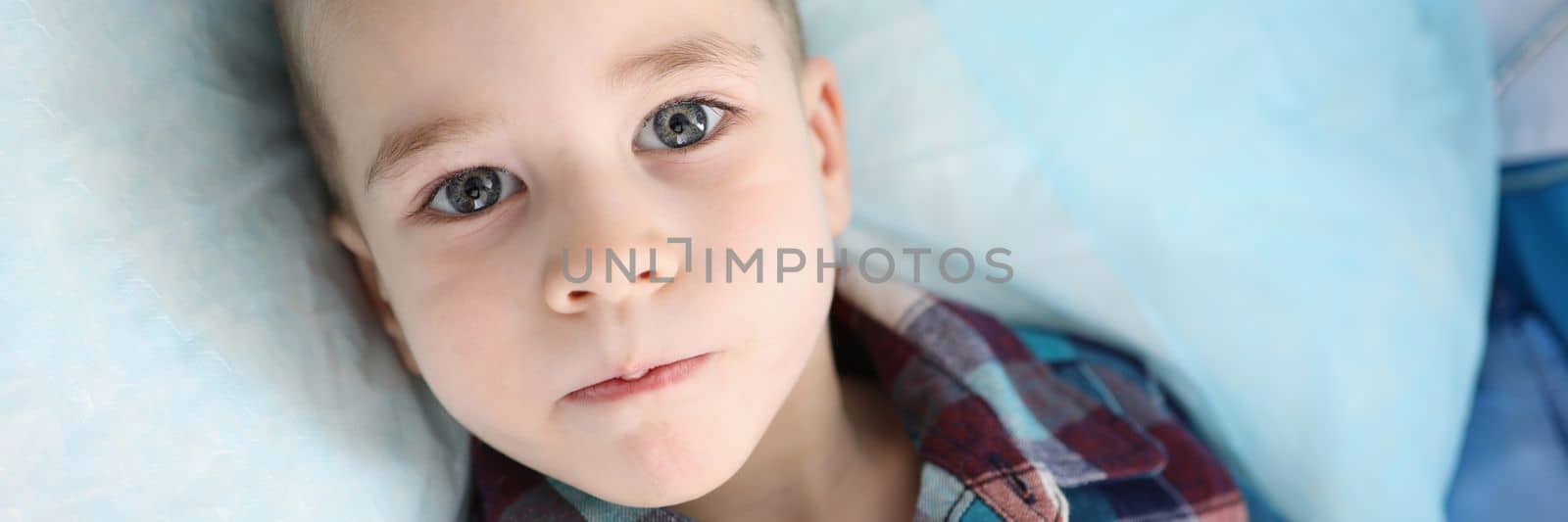 Portrait of cute little boy in colored shirt looking at camera with serious attentive face. Calm thoughtful facial expression concept