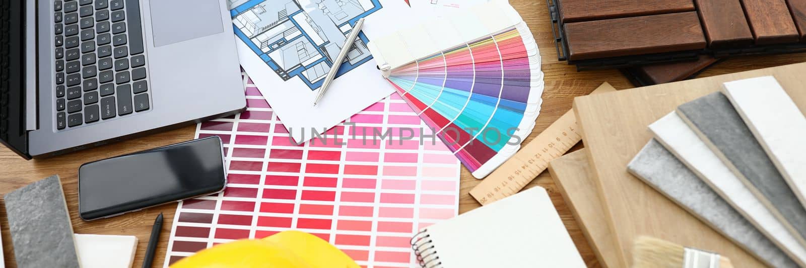 Overhead view of architect workplace drawing floor plan of modern house with material sample. Construction helmet with laptop and color palette on creative table