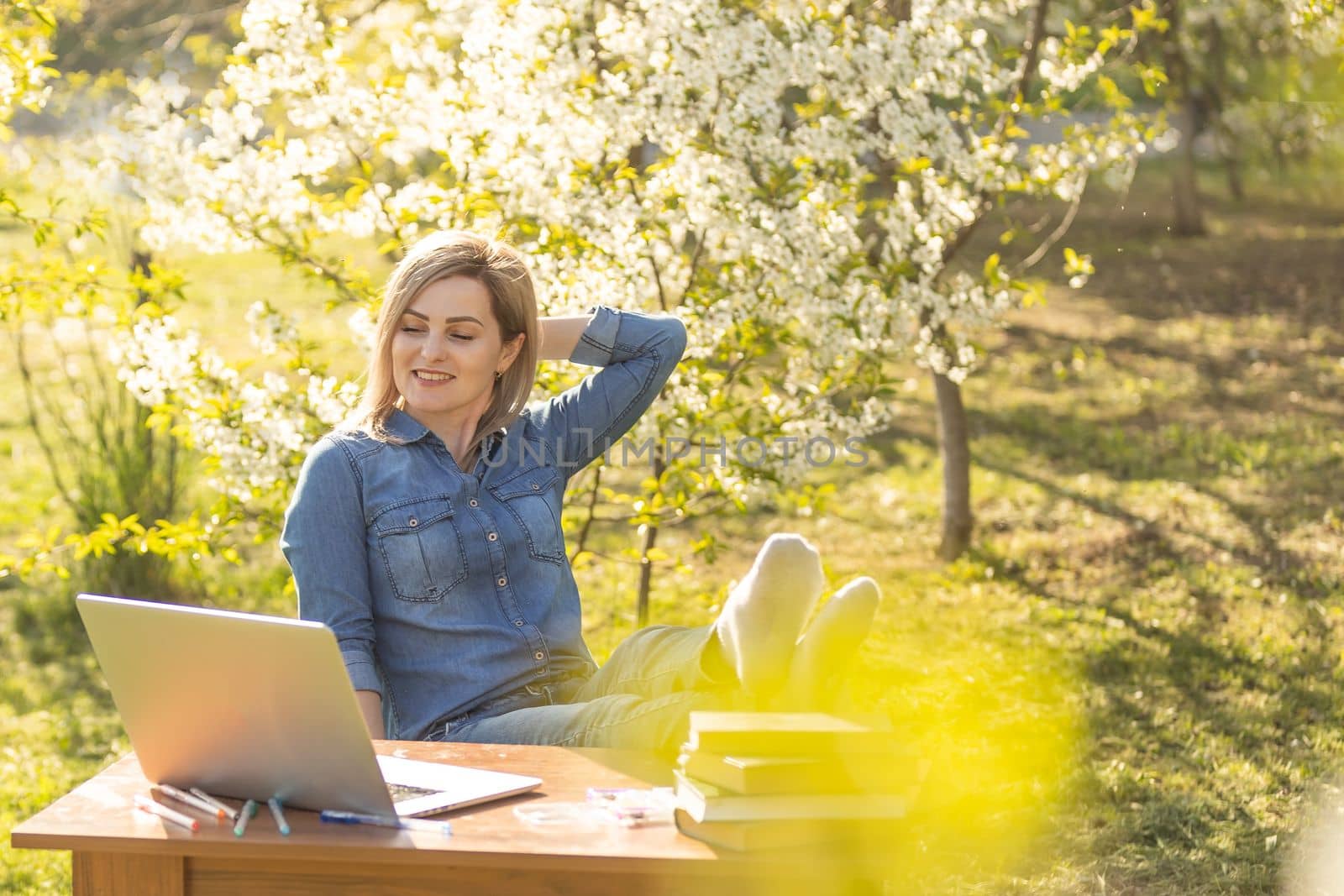 Girl with a laptop on the spring meadow