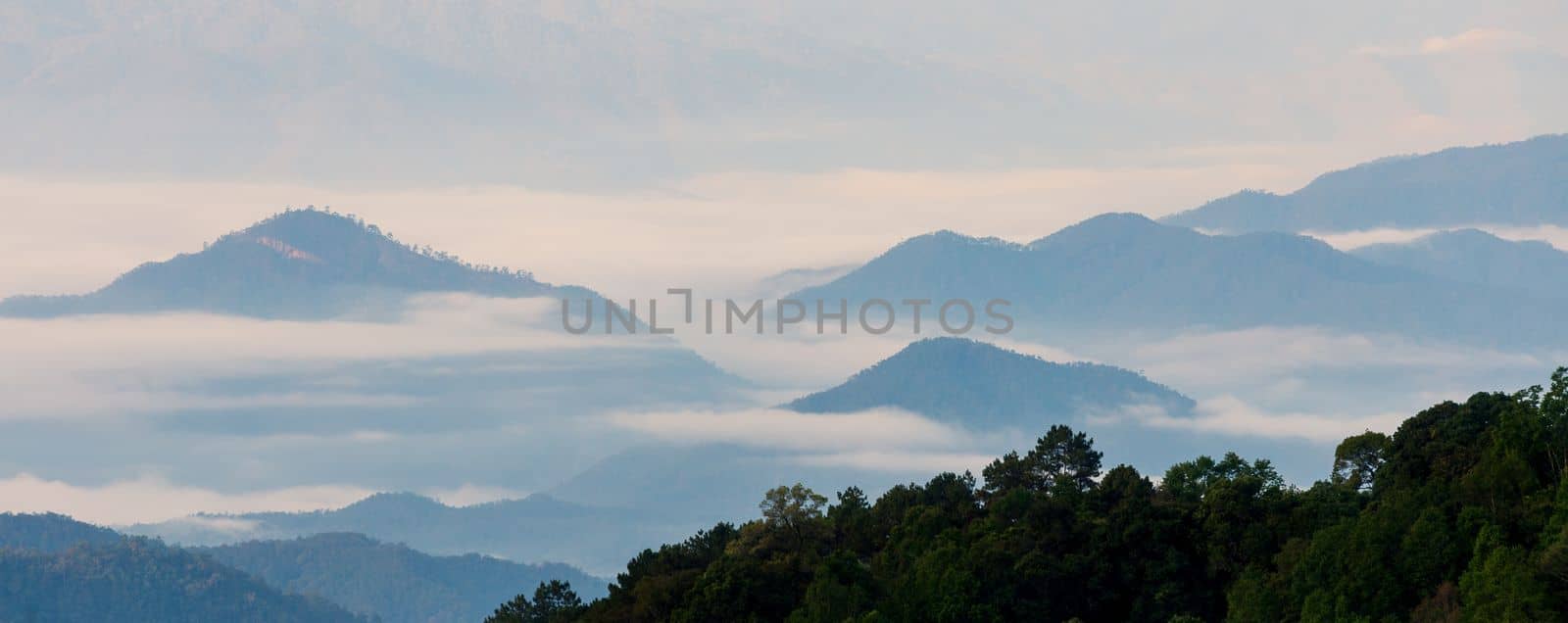 Tranquil morning landscape over the foggy mountains in tropical rainforest of Thailand.