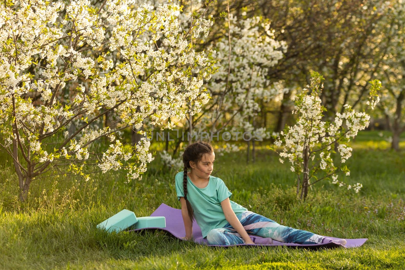 pretty girl doing yoga exercises, little girl doing yoga exercises in the garden. by Andelov13