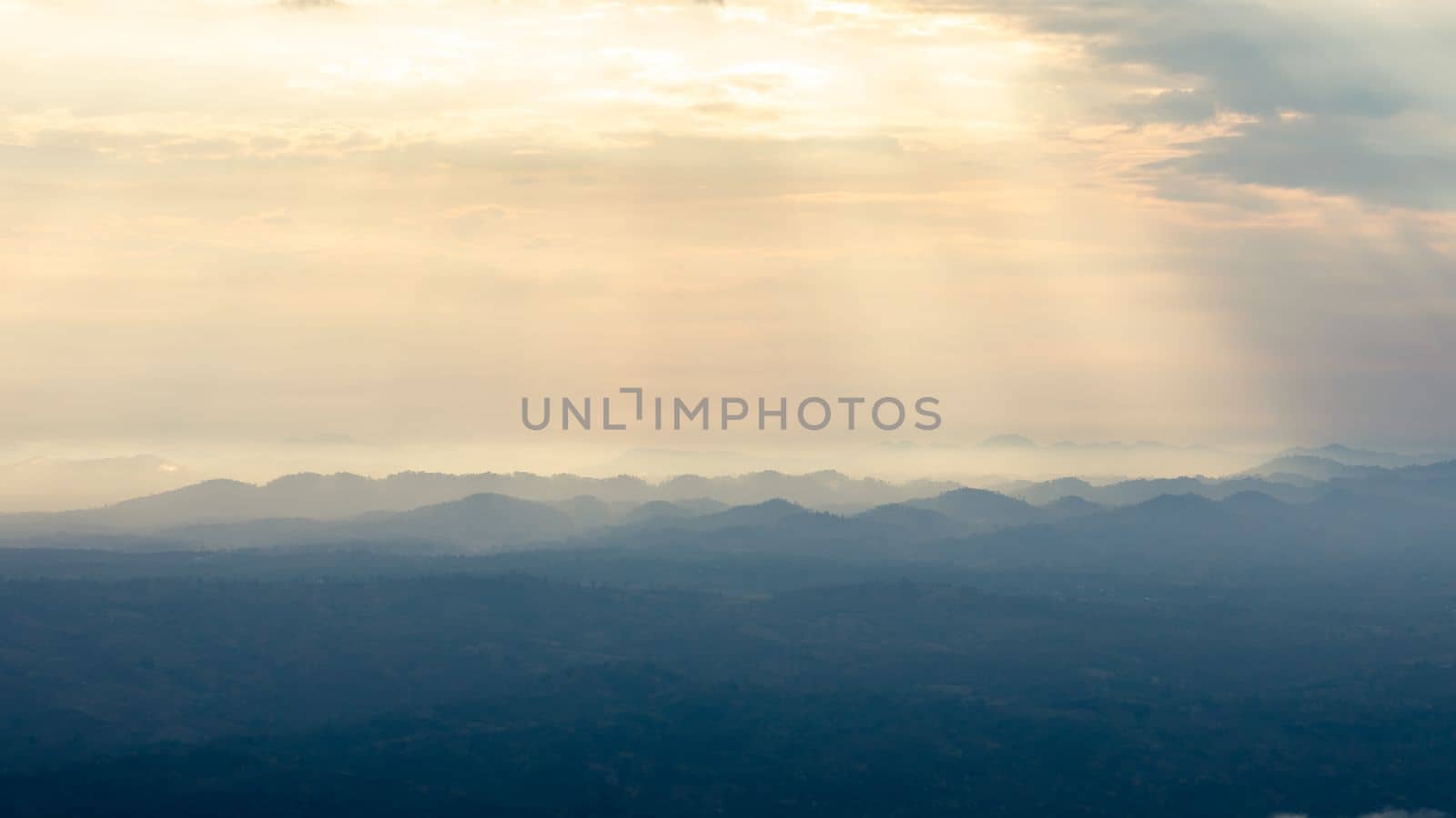 Landscape of sunbeam shining on blue mountain range before sunset.