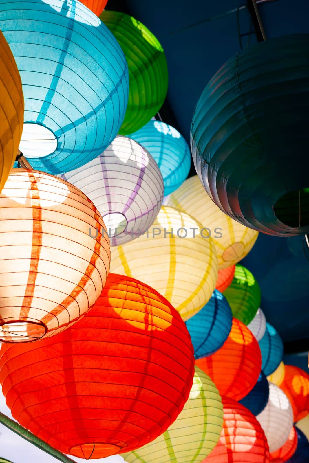Close focus on colorful globe lamps made from mulberry paper touching sunlight decorated under roof.