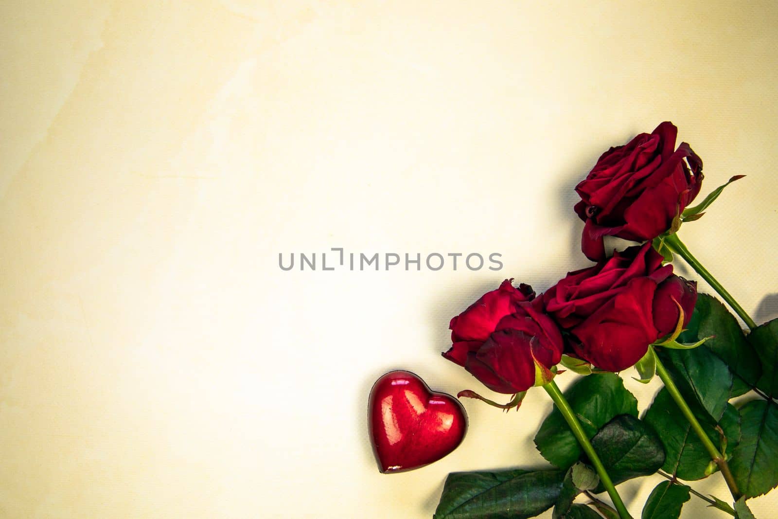 Flowers composition. Frame made of rose flowers and red heart on yellow background. Valentine's Day Mother's Day romantic background. Flat lay, top view, copy space.